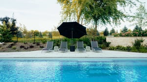 How much does a fiberglass pool cost in Kitchener, Waterloo, Ontario, Canada. Poolside lounges chairs sitting in the shade under an umbrella.